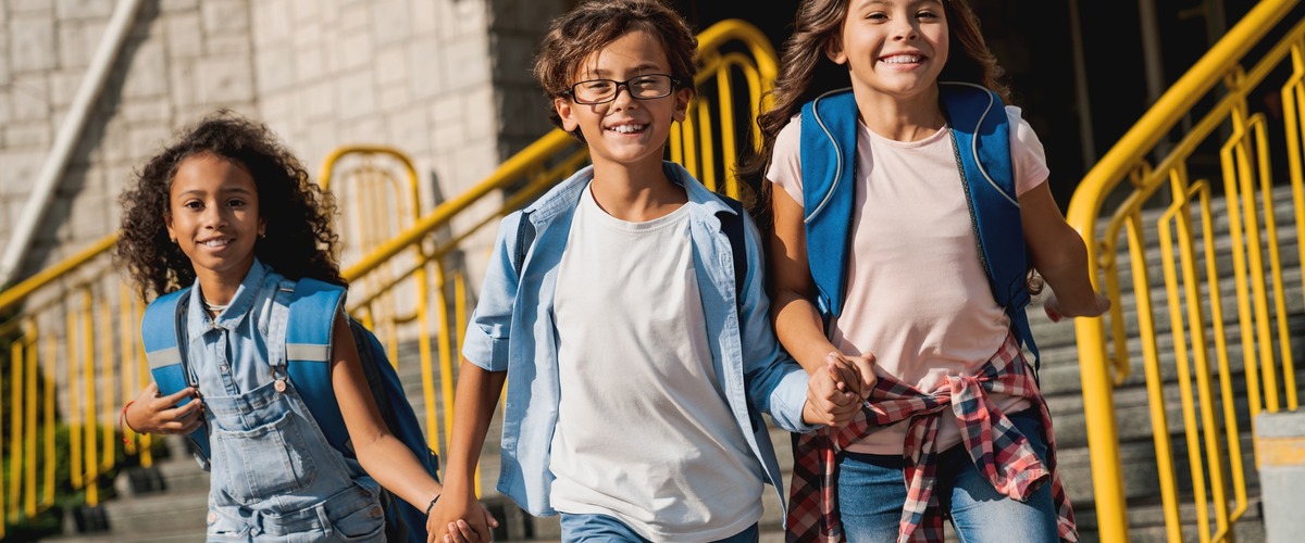 Drei Schulkinder laufen auf die Kamera zu